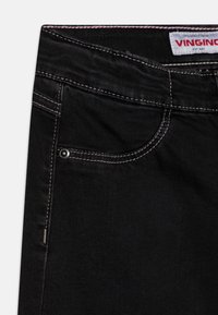 Jeans in denim nero con cuciture bianche a contrasto, tasca frontale con rivetto in metallo e etichetta con marchio sulla vita.
