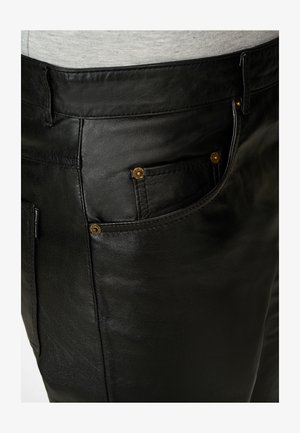 Schwarze Lederhosen mit glatter Textur, ausgestattet mit goldenen Hardware-Akzenten an den Vorderentaschen und einem klassischen Fünf-Taschen-Design.