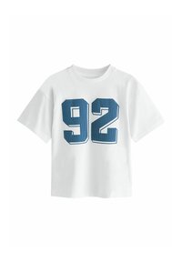 Witte katoenen t-shirt met een ronde halslijn, voorzien van gedurfde marineblauwe cijfers "92" in een stippenpatroon aan de voorkant. Korte mouwen.