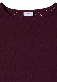 Haut en tricot violet foncé avec encolure ronde et perforations décoratives subtiles, doté d'une étiquette de marque "CECIL" blanche à l'intérieur du col.