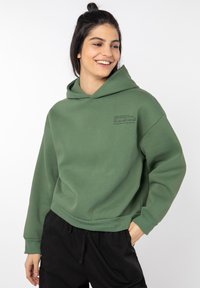 Loose-fitting green hoodie with a front pocket and print detailing. Soft fabric, long sleeves, and a drawstring hood for adjustability.