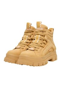 Beiget höga sneakers med platå och tjocka sulor med djupa mönster, vadderade kragar, randiga dragflikar, märkta tungetiketter och snörning framtill.