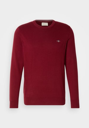 Red sweater made of cotton, featuring a round neckline and long sleeves. Includes a small logo detail on the chest and ribbed cuffs.