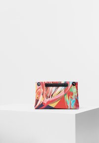 Kolorowa torba w abstrakcyjne wzory o prostokątnym kształcie, wykonana z tkaniny, z czarnym uchwytem i okrągłymi akcentami metalowymi.