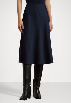 Navy A-line skirt made of smooth fabric, mid-calf length, featuring a fitted waist and subtle sheen, paired with high-heeled black boots.