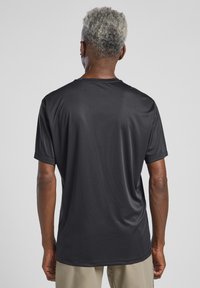Schwarzes sportliches T-Shirt aus glattem, leichtem Stoff. Kurze Ärmel, runder Ausschnitt und lockere Passform. Minimale Details.