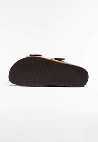 Sandale en daim marron avec une semelle en caoutchouc occulté brun foncé à nervures, dotée de deux sangles supérieures avec fermetures Velcro pour un ajustement réglable.