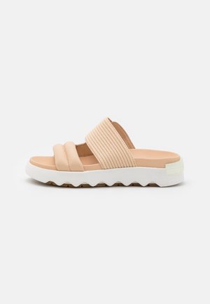 Beige åbenthå sandal med to polstrede remme og en hvid tyk sål med bølget mønster.