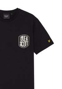 Maglietta nera in cotone con un logo ricamato circolare con "LYLE & SCOTT" in bianco sul petto e un piccolo emblema giallo sulla manica.