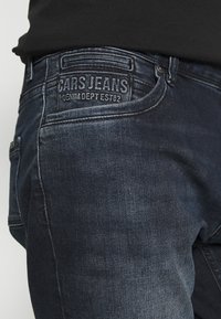 Tmavě modré džínsy vyrobené z denimu, s jemným vyblednutím a detaily šití. "CARS JEANS" reliéfně vyražené na zadní kapse.