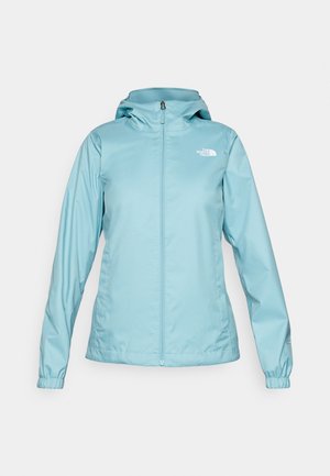 Veste imperméable bleu clair avec capuche, fermeture éclair sur toute la longueur à l'avant, poignets élastiques et logo affiché de manière bien visible en haut à gauche.