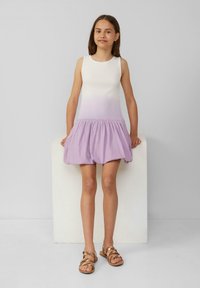 Robe sans manches avec un dégradé de blanc à lavande, présentant une jupe lavande froncée. Modèle portant des sandales brunes à lanières.
