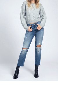 Light gray, textured knit sweater with pearl accents, paired with light blue distressed jeans featuring torn knees and black ankle boots.