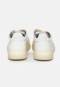 Sneaker bianche e crema con retro testurizzato, caratterizzate da una finitura glitterata e un branding sottile sul tallone. Design classico con lacci.