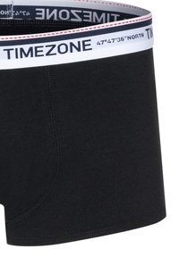 Black boxer briefs made of soft fabric feature a contrasting white waistband with printed text, including "TIMEZONE" and geographic coordinates.