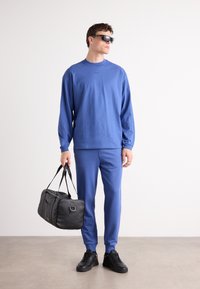 Blue cotton long-sleeve shirt and matching pants. Black leather bag with dual handles. Black sneakers. Simple design, smooth texture.