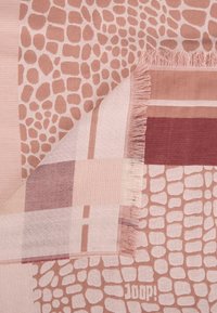 Textile présentant un mélange de tons roses et de motifs, comprenant des rayures en blocs lisses et des formes abstraites, fini avec des détails en franges.