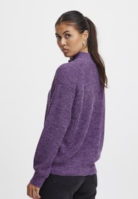 Paarse gebreide trui met een hoge hals, lange mouwen en een relaxed fit. Getextureerde stof met lichte kleurvariaties.