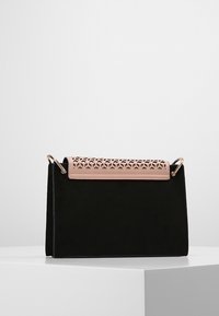 Borsa in suede nero con patta in pelle rosa dal taglio geometrico. Presenta dettagli in oro e una forma rettangolare strutturata.