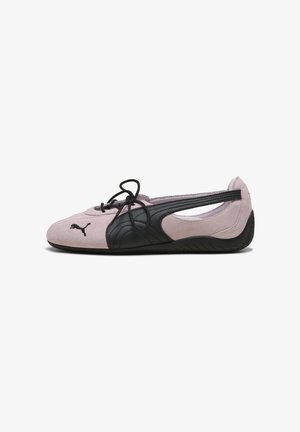 Chaussure Puma à semelle souple rose clair et noire avec un design latéral ouvert et des lacets noirs, vue de côté sur fond blanc.