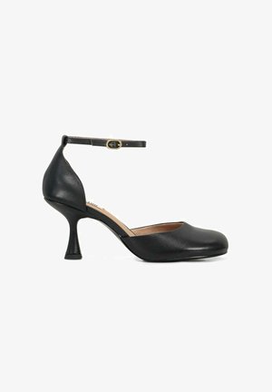 Décolleté in pelle nera con tacco medio, punta arrotondata, cinturino alla caviglia e fibbia dorata, mostrata su sfondo bianco.