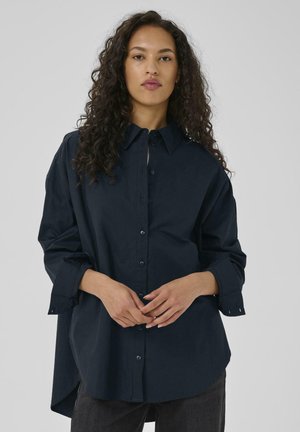 Navy blue button-up shirt with a collar, long sleeves, and a curved hem. Made of lightweight fabric, featuring a relaxed fit and subtle texture.