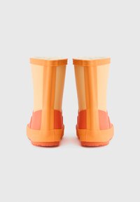 Oranžne gumene škornje za dež, z teksturiranim podplatom, z ogrevanjem iz krzna na vrhu in temnejšim oranžnim trakovanjem na dnu.