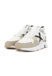 Scarpe da ginnastica bianche e beige realizzate in mesh e camoscio, con strisce nere a contrasto e suola in gomma texturizzata. Presentano un design con lacci.