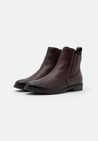 Bottes en cuir marron à la cheville avec fermeture éclair sur le côté, panneau élastique, bout arrondi et petit talon avec des détails de surpiqûre discrets.