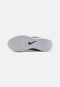 Suola di sneaker Nike con un design in gomma grigia texturizzata, caratterizzata da un logo swoosh nero e motivi di presa circolari nell'intera superficie.