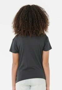 Zwarte T-shirt met korte mouwen en een standaard pasvorm, met een gladde textuur. De zoom is aan de achterkant iets gebogen.