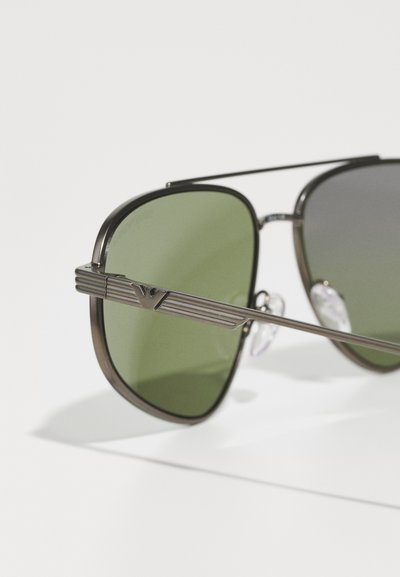 Metal-framed sunglasses feature dark green lenses, a rectangular shape, and textured accents on the temples. Clear nose pads included.