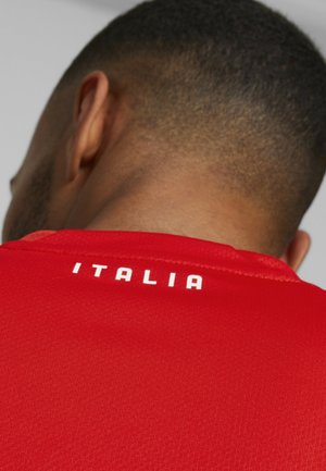 Rood sportshirt met een gestructureerde stof, met het woord "ITALIA" in witte hoofdletters op de achterkant van de kraag.