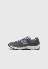 Buty sportowe w ciemnym niebieskim i szarym kolorze, z siateczkowymi i zamszowymi materiałami, teksturowaną podeszwą środkową oraz wyraźnym logo marki z boku.