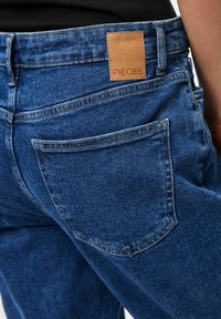 Denim jeans in medium blue with a leather label marked "PIECES" at the waistband, featuring back pockets and a straight cut.
