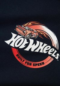 Hot Wheels grafika, kurā attēlots oranžs auto ar liesmām, uz tumšzilga fona. Uzraksts: "HOT WHEELS" un "BUILT FOR SPEED".