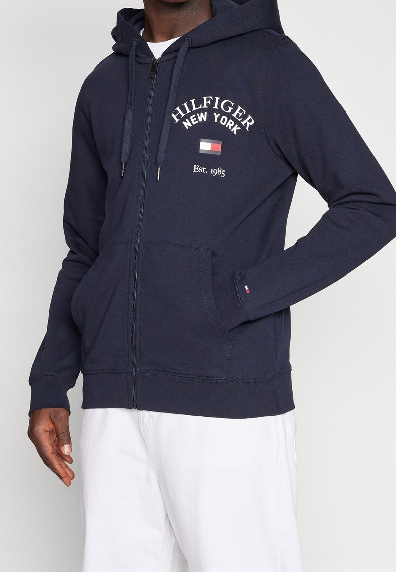 Sudadera con capucha y cremallera en tejido suave, con texto blanco "Hilfiger New York", bolsillo delantero y capucha con cordón. Puños y bajo acanalados.
