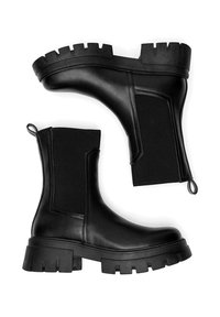 Botines negros confeccionados en cuero y tela elástica, con una suela gruesa de diseño acanalado y una lengüeta para facilitar su colocación.