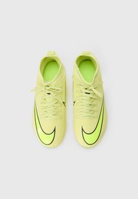 Zapatos de fútbol amarillos con una textura suave y el logotipo de Nike en negro. Presenta un diseño con cordones y un collar acolchado para mayor comodidad.