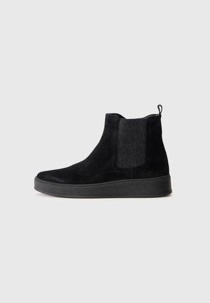 Black suede Chelsea boot with elastic side panels, pull tab at heel, and flat textured sole, shown in side profile on plain background.