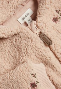 Roze fleece zip-up jack met een zachte textuur, voorzien van bloemenborduursel en geribbelde boorden. Label toont maat 80 (9-12 maanden) en merknaam "newbie."