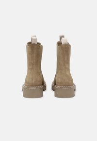 Semišové kotníkové boty v khaki barvě s hladkým povrchem. Mají zaoblenou špičku, robustní gumovou podrážku a poutka na zadní straně.