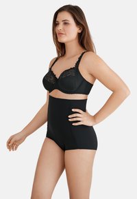 Set di lingerie nera composto da un reggiseno con dettagli in pizzo e bordo ondulato, abbinato a un perizoma alto in un tessuto liscio e senza cuciture.