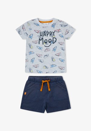 Conjunto infantil con camiseta gris que presenta estampados de zapatillas de colores y texto "HAPPY MOOD", combinado con pantalones cortos azul marino con cordón naranja.