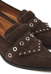 Bruine suède loafers met een franjes ontwerp, metalen oogjes en decoratieve studs. De schoenen hebben een spitse neus en een platte zool.