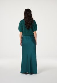 Teal gebreide trui met korte mouwen en een fuzzy textuur, gecombineerd met een satijnen teal maxi-jurk. Glad afwerking en stijlvolle silhouet.