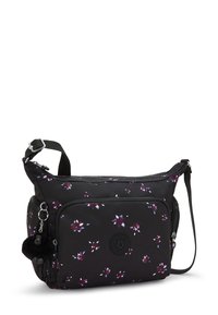 Borsa di stoffa nera con motivo floreale in viola e bianco. Presenta una tasca frontale con zip, una tracolla regolabile e un logo rotondo sul davanti.
