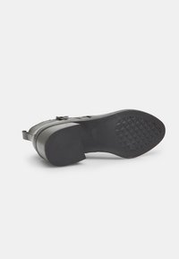 Suela de zapato de goma negra con un patrón texturizado, que presenta una parte superior lisa y un talón robusto y ligeramente elevado para mayor estabilidad.