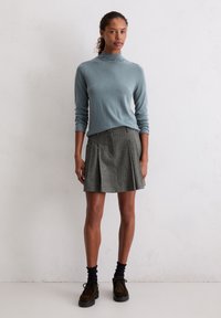 Lichtblauwe high-neck trui, geplooide grijze minirok, zwarte enkelsokken en bruine schoenen. Eenvoudig ontwerp met gladde texturen.