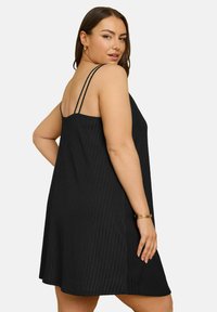 Musta teksturoitu mekko säädettävillä ohutolkaimilla, A-linjan muoto ja lievä leveneminen helmaan. Huomionarvoista on sen uritettu kangas.